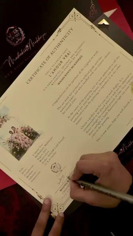 A hand signing the numbered Certificate of Authenticity in ink