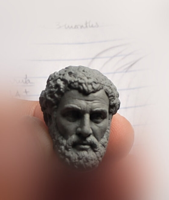 Held between two fingers — a philosopher the size of a thumbnail